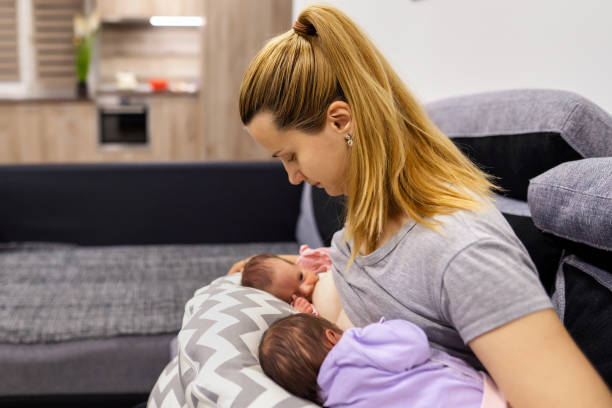 Mother holding and breastfeeding her twin babies.