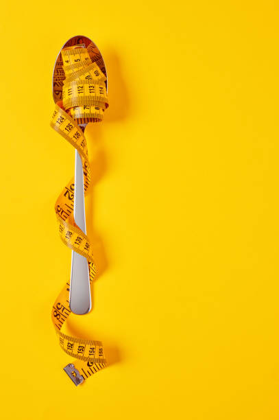istock spoon with tape measure on yellow 1324733238