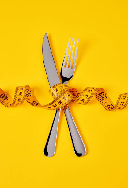 istock Tape measure, fork and knife on yellow background 1324733260