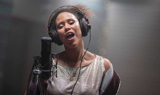 Adult female singer in recording studio. Woman expressing her emotions with gesture. Music, arts and entertainment concept.