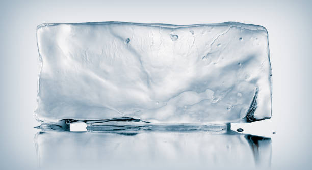 un gran rectángulo de hielo claro que se derrite, sobre fondo blanco con un reflejo de espejo. concepto creativo de pureza fría. - blue transparent cold cube fotografías e imágenes de stock