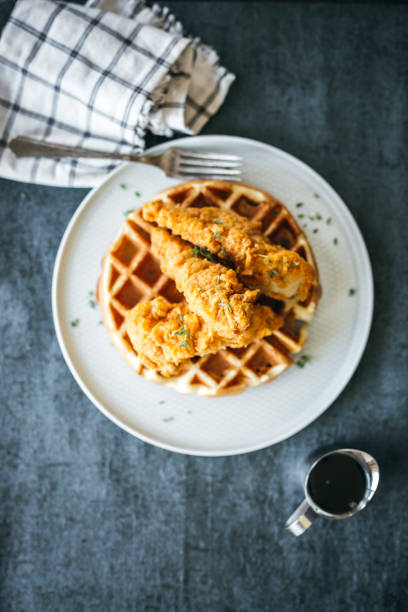 gourmet chicken and waffles plated restaurant style with side of syrup in silver pitcher - waffle breakfast food sweet food imagens e fotografias de stock