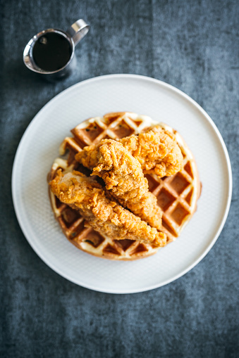 Above View of Crispy Fried Chicken Over Belgian Waffles with Butter and Maple Syrup