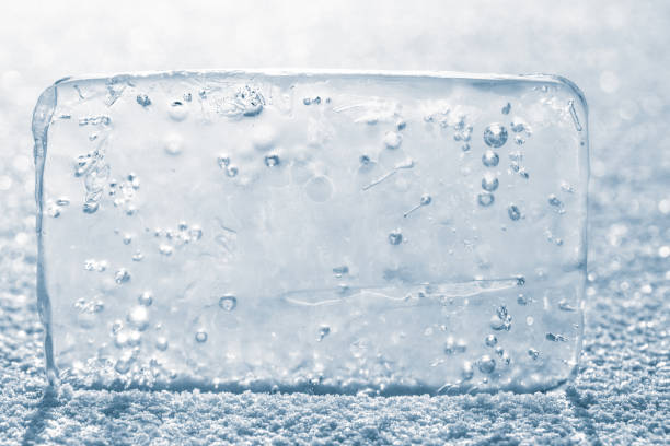 istock The rectangular block of pure transparent ice with air bubbles in cold blue tones on a winter river ice, covered with white snow. 1324737276