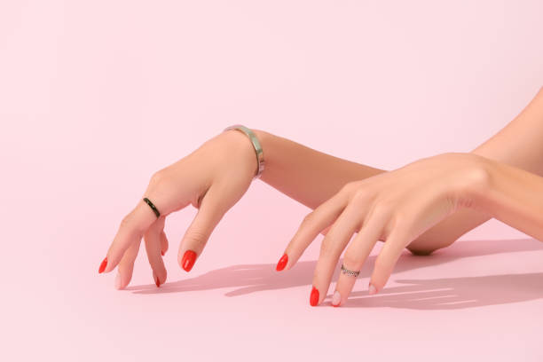 istock Womans hands with red manicure on pink background. Manicure design trends 1324737312