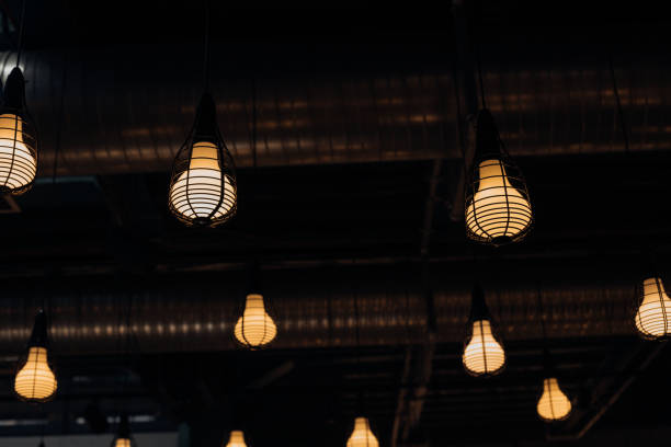 istock Large light bulbs burn yellow under ceiling at night. Group of objects. Light and decoration. 1324737471