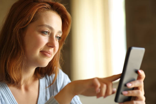 istock Redhead woman using smart phone at home 1324737530