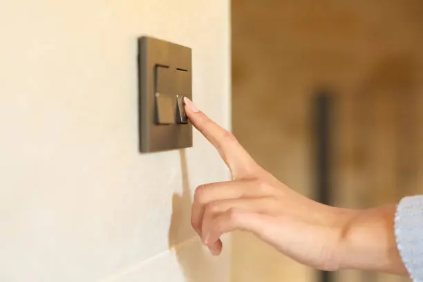 Woman hand pushing light switch at home