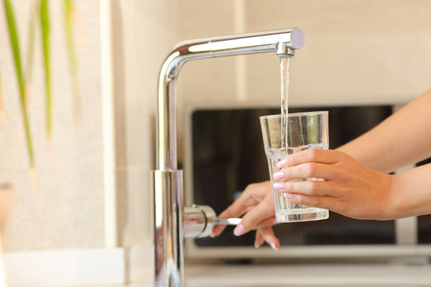 mani donna che riempiono un bicchiere di acqua del rubinetto - rubinetto foto e immagini stock