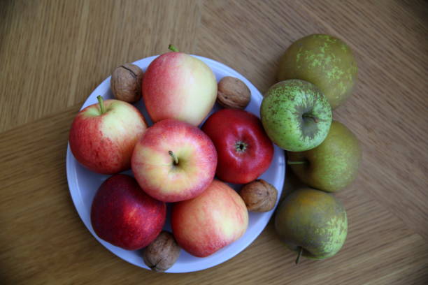 istock Still life with different qualities of apples and walnuts on a wooden surface 1324738621