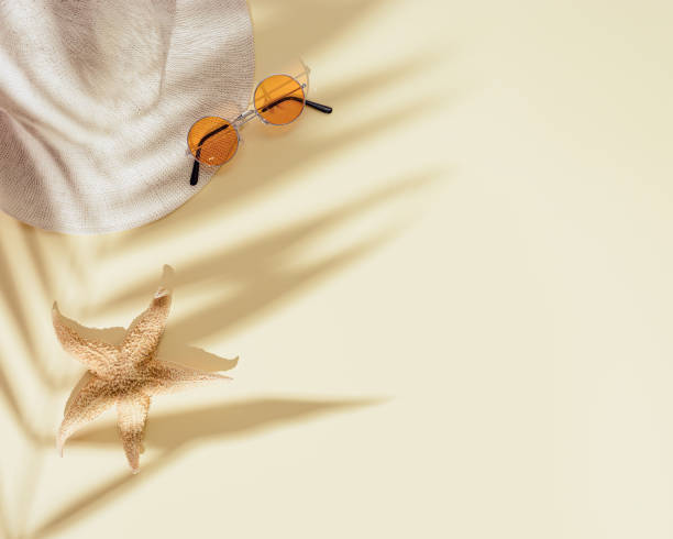 istock Summer flat lay with sun hat, colored sunglasses, starfish on sandy color background 1324739500