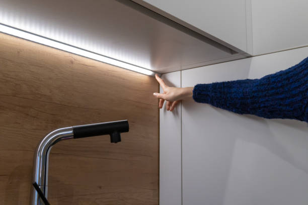 kobieca ręka zawiera pasek led do oświetlenia na powierzchni szafy na zestawie kuchennym - removing house furniture home interior zdjęcia i obrazy z banku zdjęć