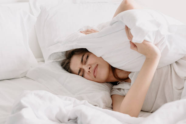 istock Young woman covers her ears with a pillow 1324748129