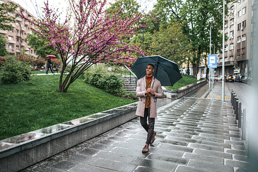 Beautiful and happy businessman walking on the rainy day