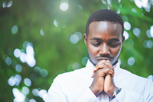 African man praying for thank god in the green nature