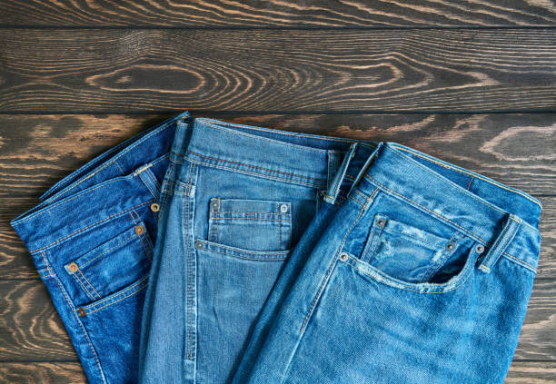 istock Blue jeans in a row, stack of denim pants, composition on wooden background with copy space 1324752284