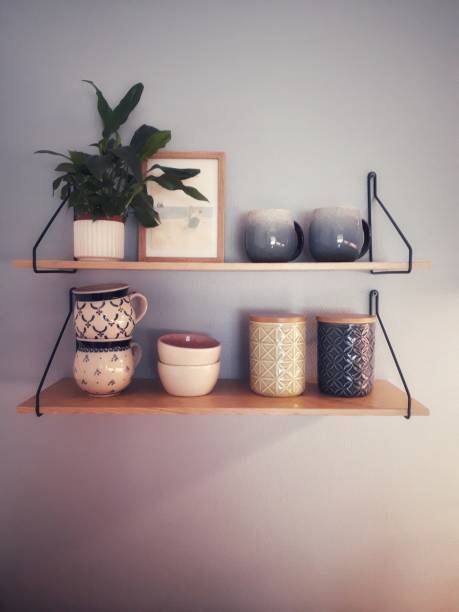 istock Kitchen shelves on blue wall. Plant, picture and cups 1324755994
