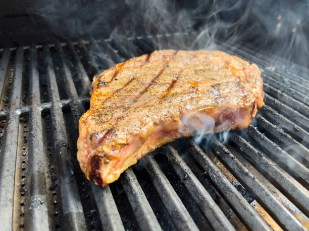 Thick Cut Raw Seasoned Beef T-Bone Steaks On A Charcoal Grill With Flames Photo Series