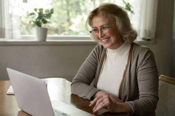 istock Smiling old woman talk on webcam call on laptop 1324756609