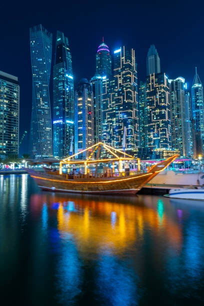 ночной вид на панораму дубай марина и традиционную деревянную лодку оаэ. роскошные небоскребы представляют собой современный дубай. удиви� - dubai skyline united arab emirates finance стоковые фото и изображения
