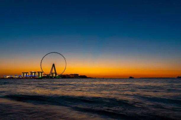 Amazing sunset colors over the sea view to the Ain Dubai, giant Ferris at artificial island Bluewaters Island  close to JBR beach. Dubai Eye fits perfect to modern UAE skyline