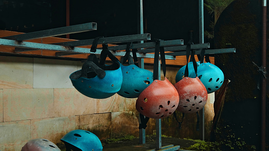 Colored protective helmets for the head to practice rafting hanging on the wall