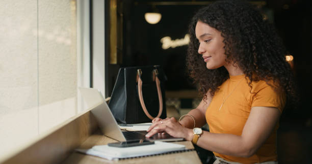 istock Shot of a young woman using her laptop while sitting in a coffeeshop 1324760480
