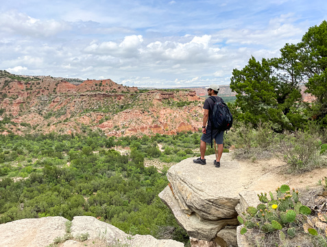 Close up view of hiker standing on top of the cliff of Lighthouse Trail and overlook the canyon in Palo Duro Canyon State Park