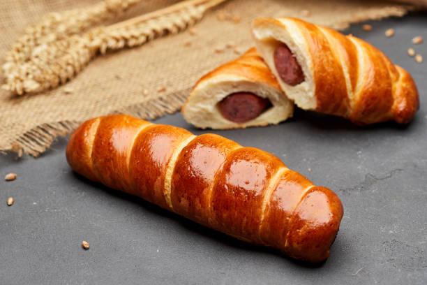 暗い背景にパフペストリーで焼いた生地でロールアップホットドッグソーセージ - blanket pig hot dog sausage ストックフォトと画像