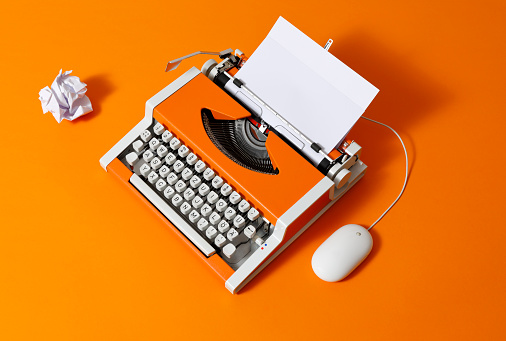 70s typewriter with crumpled paper ball and a computer mouse