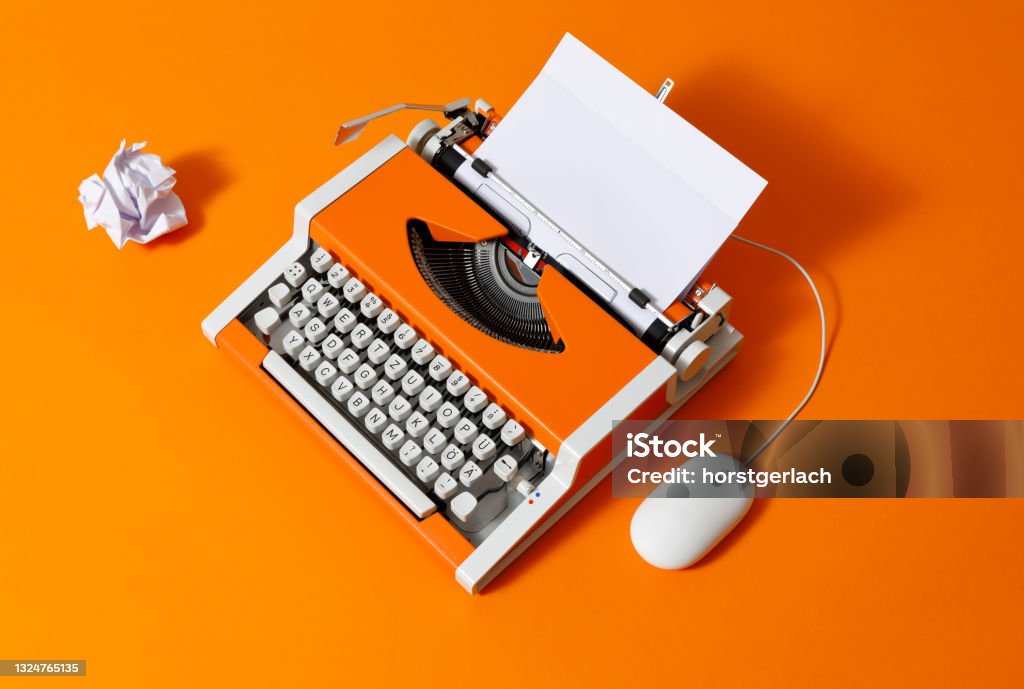 Orange 70s Typewriter with blank Page 70s typewriter with crumpled paper ball and a computer mouse Typewriter Stock Photo