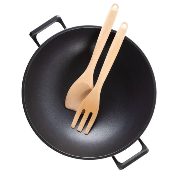 istock Wooden spoon and fork on a pan isolated on white. 1324766080