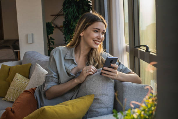 istock Young woman relaxing on the couch and using smart phone 1324767710