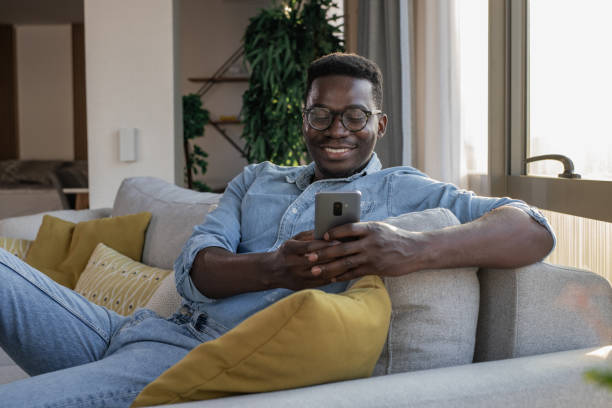 istock Young man relaxing on the couch and using smart phone 1324767752