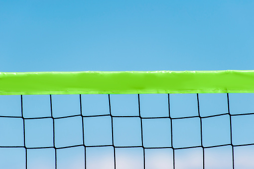 Beach volleyball and beach tennis net on the background of blue sky with clouds. Summer sport concept.