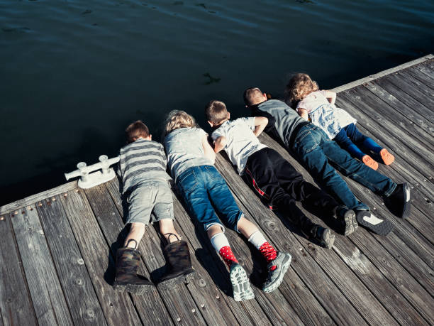 istock Children Lay on Ground Looking Over Dock Edge 1324775983