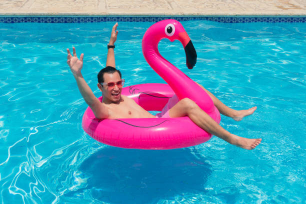 istock A man has fun on a fuchsia flamingo inflatable float in the pool. 1324776162