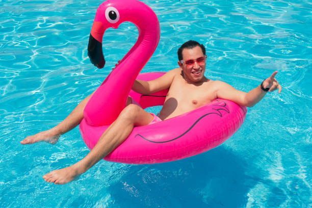 istock A man has fun on a fuchsia flamingo inflatable float in the pool. 1324776215