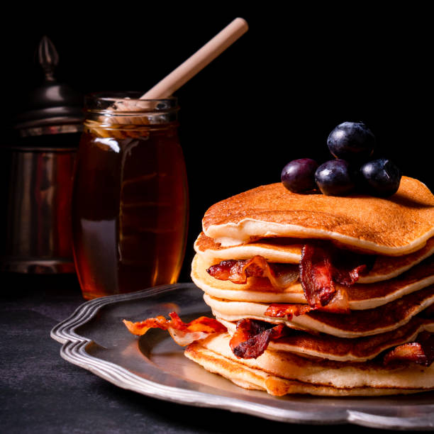 istock Fresh homemade pancake stack with crispy organic bacon and blueberry fruit butter drippings honey maple syrup for tasty sweet morning breakfast with American traditional authentic style 1324776808