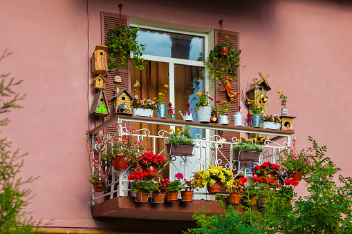 A picturesque balcony of the house, decorated with flowers and various objects.