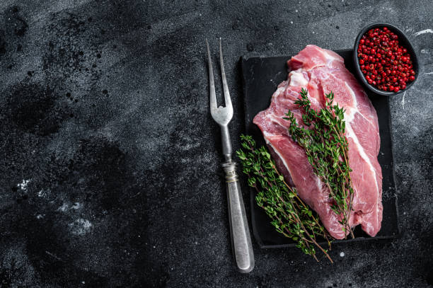 istock Raw pork shoulder meat cut on a marble board. Black background. Top view. Copy space 1324779358