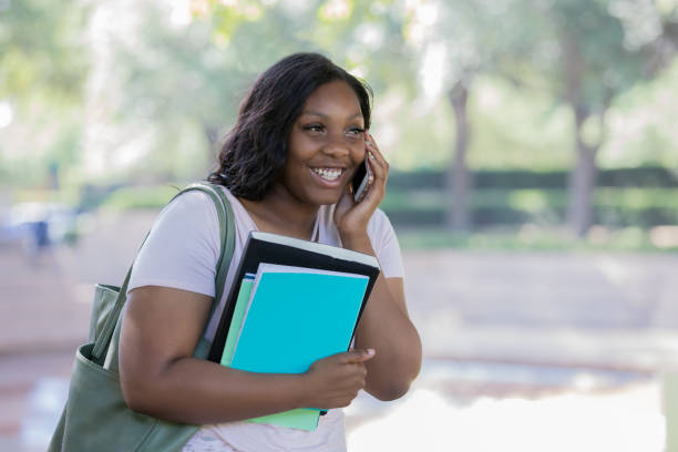 istock College student holding her books and talking on her cell phone 1324779534