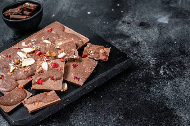 istock Craft homemade chocolate bars chopped on marble board. Black background. Top view. Copy space 1324780318