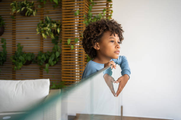 istock Sad afro boy looking outside during quarantine of Covid-19 1324780468
