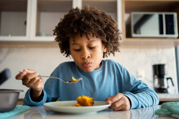istock Beautiful afro young boy eating cake at kitchen 1324780496