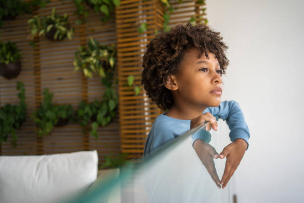 istock Sad afro boy looking outside during quarantine of Covid-19 1324780569