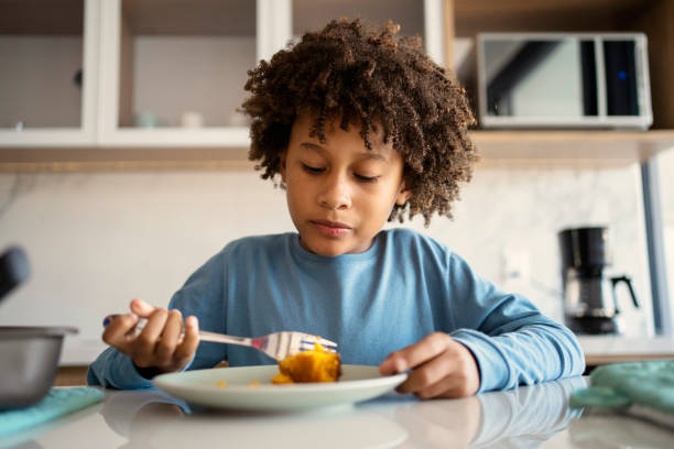 istock Beautiful afro young boy eating cake at kitchen 1324780605