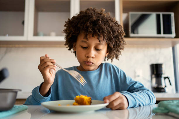 Beautiful afro young boy eating cake at kitchen