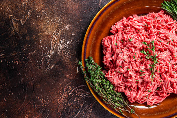 istock Raw ground beef or veal meat on a rustic plate with herbs. Dark background. Top view. Copy space 1324781374