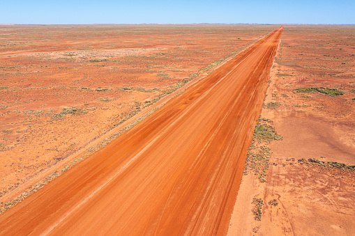Aerial view of red centre desert region with straight road at Coober Pedy, South Australia, with straight dirt road.